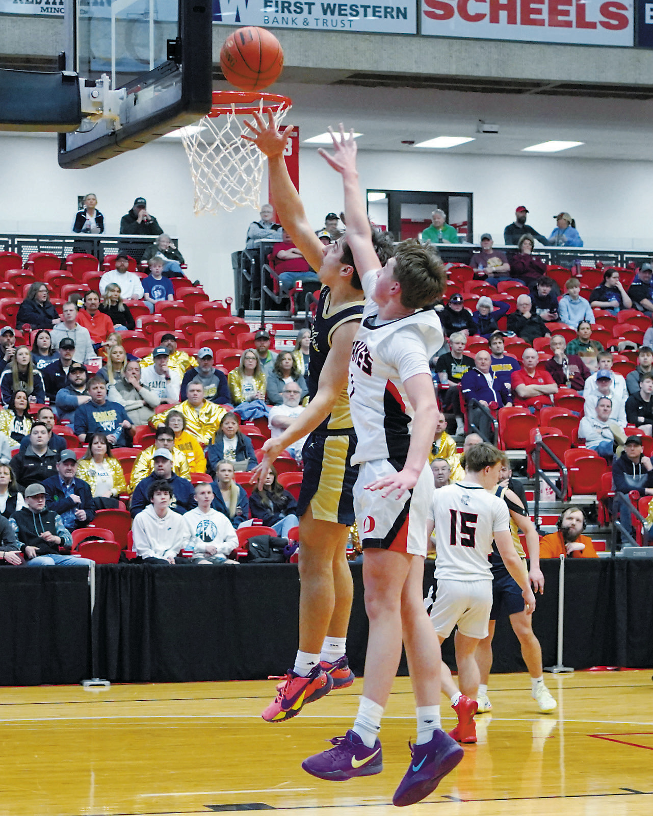 Weston Cosley finger tip rolls a basket in under pressure from an Oakes player. Photo by Larry Stokke.