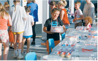 A young participant celebrates after winning a cake during the Pre-Blast Bash cake walk. The Bread Pan Bakery donated 20 cakes for the popular community event. Photo by Larry Stokke