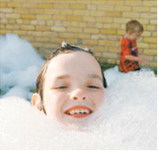 A young attendee is nearly buried in bubbles during the foam party at the Pre-Blast Bash, one of the day's most popular attractions for children. Photo by Larry Stokke.