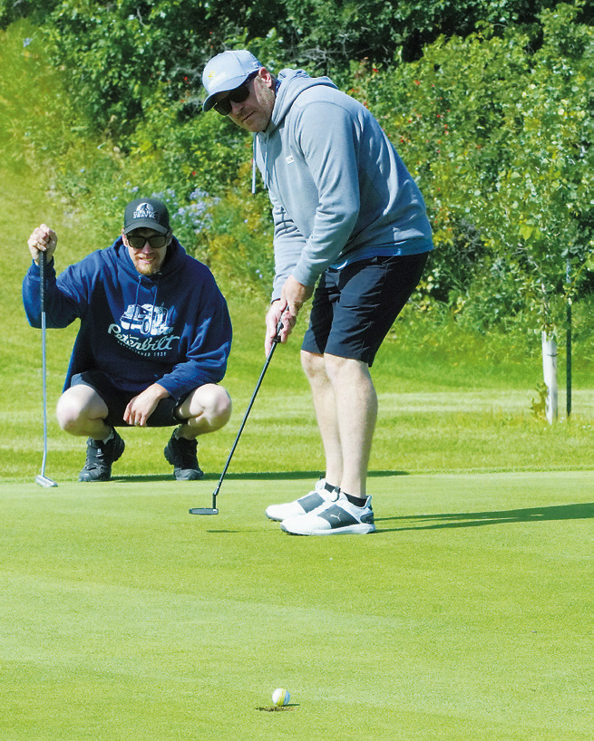 Jim Brown sinks a putt while Ryan Girodat watches closely. Photo by Larry Stokke.