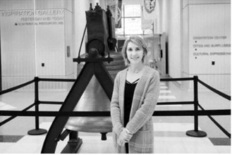 Melissa Klocke-Joyce, program coordinator for the ND250 Commission, stands next to a replica of the Liberty Bell at the North Dakota Heritage Center on Dec. 22, 2025. (Photo by Michael Achterling/North Dakota Monitor)