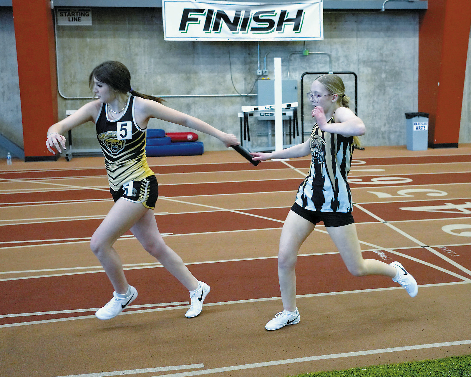 Eliot Peterson hands the baton off to Amelie Willits. Along with Nevaeh Schroeder and Leah Schroeder, the team placed 9th in the 4x300 relay on April 4 in Grand Forks. Photo by Larry Stokke.