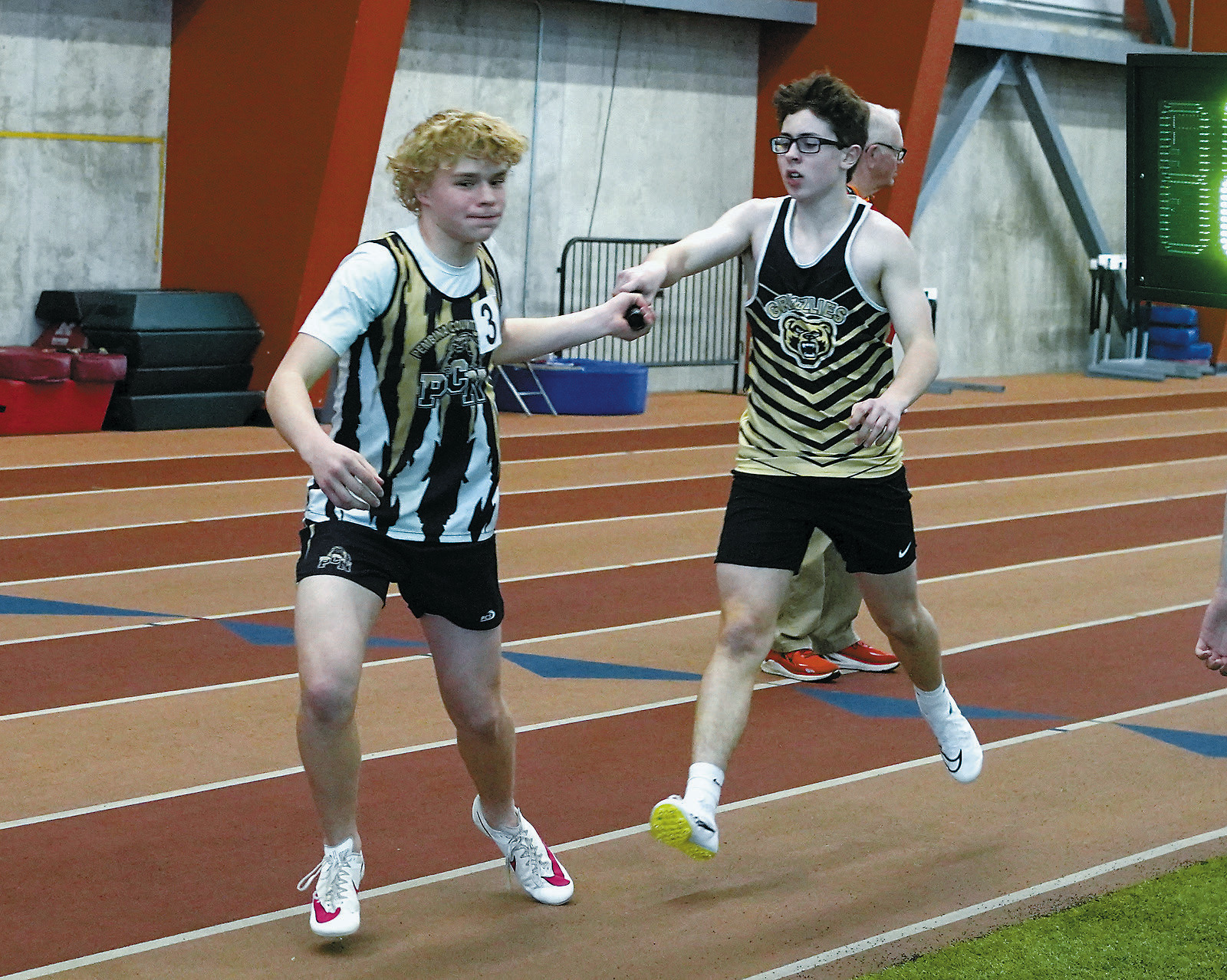 Logan Heuchert hands the baton to Kylan Schafer in the 4X300 relay. Photo by Larry Stokke.