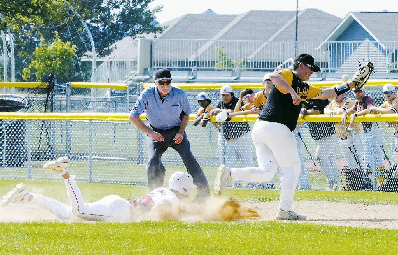 Cody Amble dives back safely to first base on a missed catch in the game against Park River. Photo by Larry Stokke.