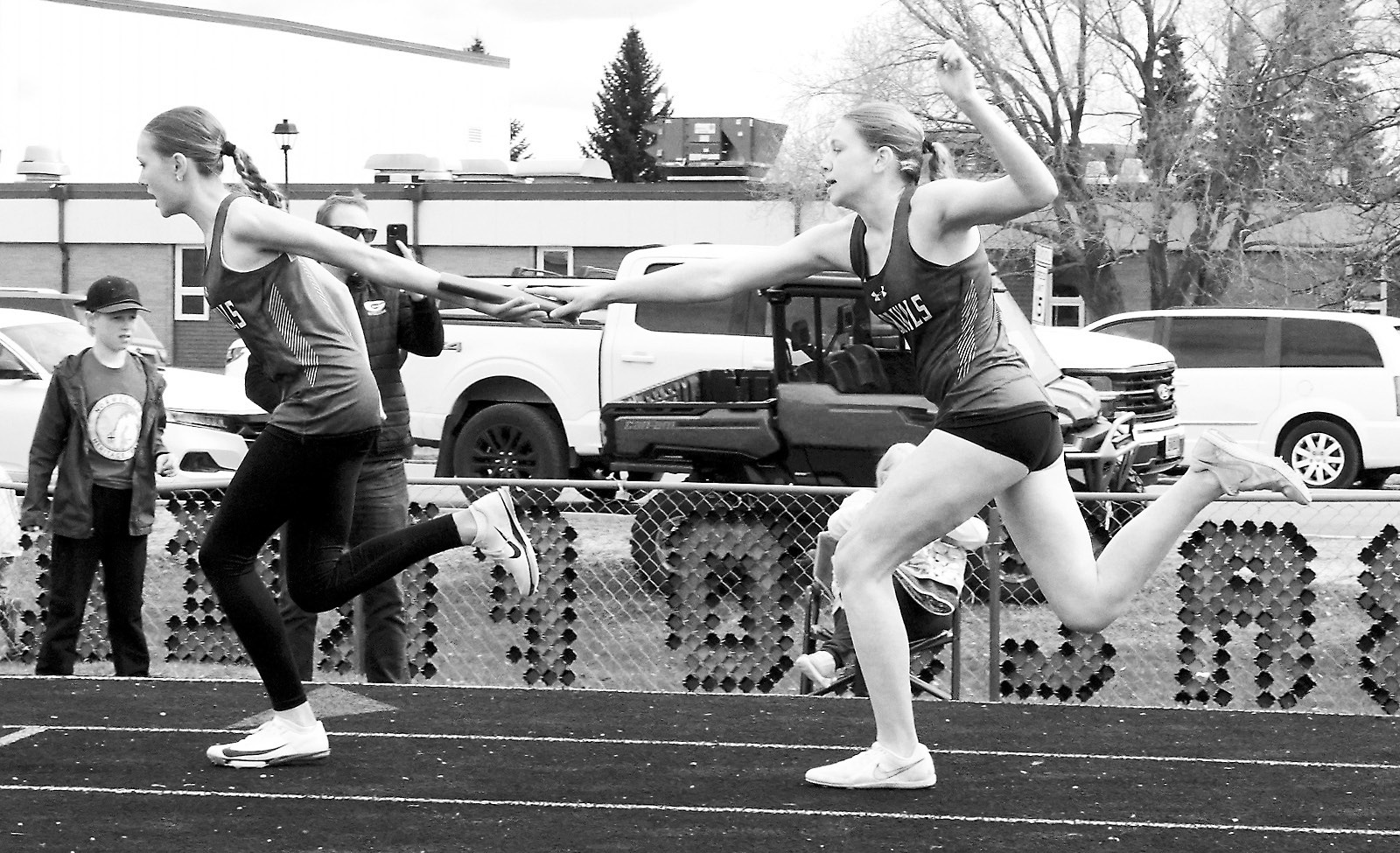 Hallie Overby hands the baton to Ary Schaefer who, with teammates Chloe Koons and Erika Bakke, took 2nd place in the 4X200 meter relay at the Langdon Invitational on April 24. Photo by Larry Stokke