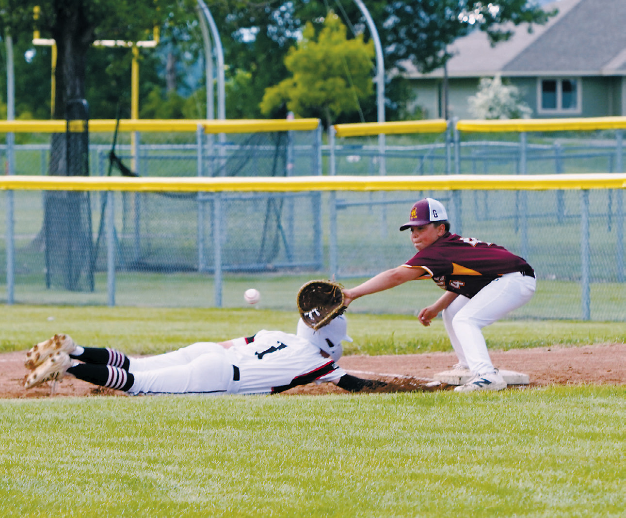 Bensen Fetsch dives safely back to the bag ahead of the throw during Langdon's game against Grafton on June 23. Photo by Larry Stokke