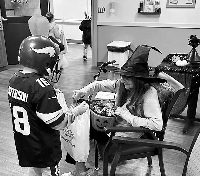 Rose, dressed up as a witch, hands out candy to a trick-or-treater