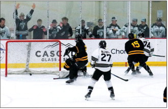 Kennen Forest sends the puck into the Stallions net to score with the Blades past and current players cheering him on. Photo by Larry Stokke