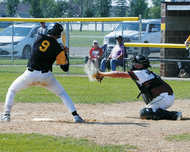 Landon Schneider raises dust as he makes a catch against a Park River player in Grafton. Photo by Larry Stokke.