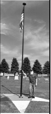Pinky Padden stands beside the flagpole he purchased and installed at the Lebanon Cemetery east of Langdon. Padden also provided the flag and light and painted the Eastern Star emblem at the base as a tribute to all veterans. Photo submitted by Kevin Stein