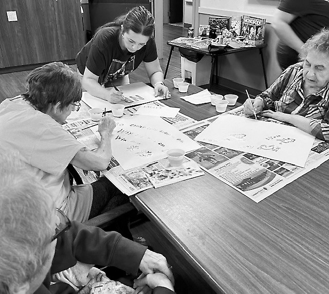 Residents and Kelsey working on painting their posters for homecoming at North Border Walhalla.