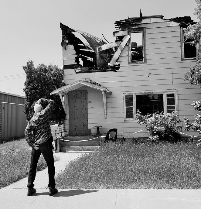 An alleged unidentified passerby studying the burned out ruins of the former two-story apartment building on Third Street.