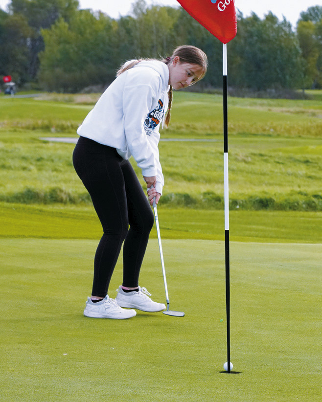 Nadia Lewis sinks a putt and finished the day with a score of 99, qualifying her for the state tournament. Photo by Larry Stokke.