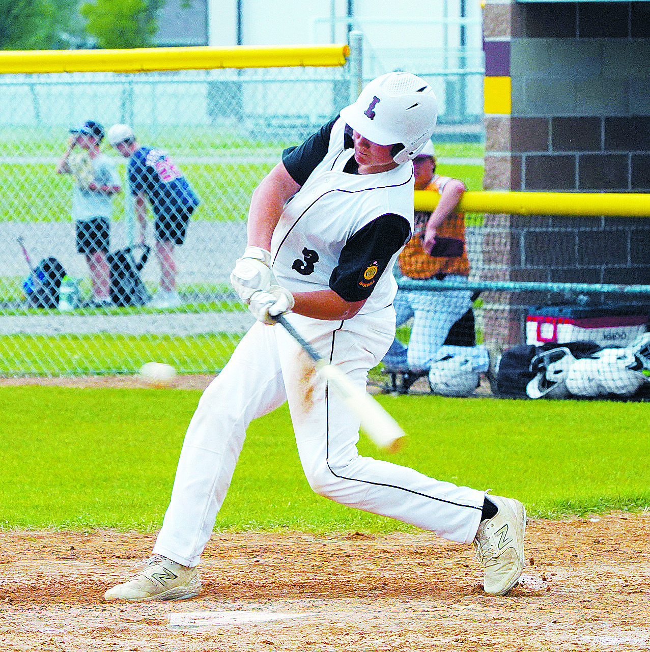 Landon Schneider drives one into the outfield to get on first base. Photo by Larry Stokke.