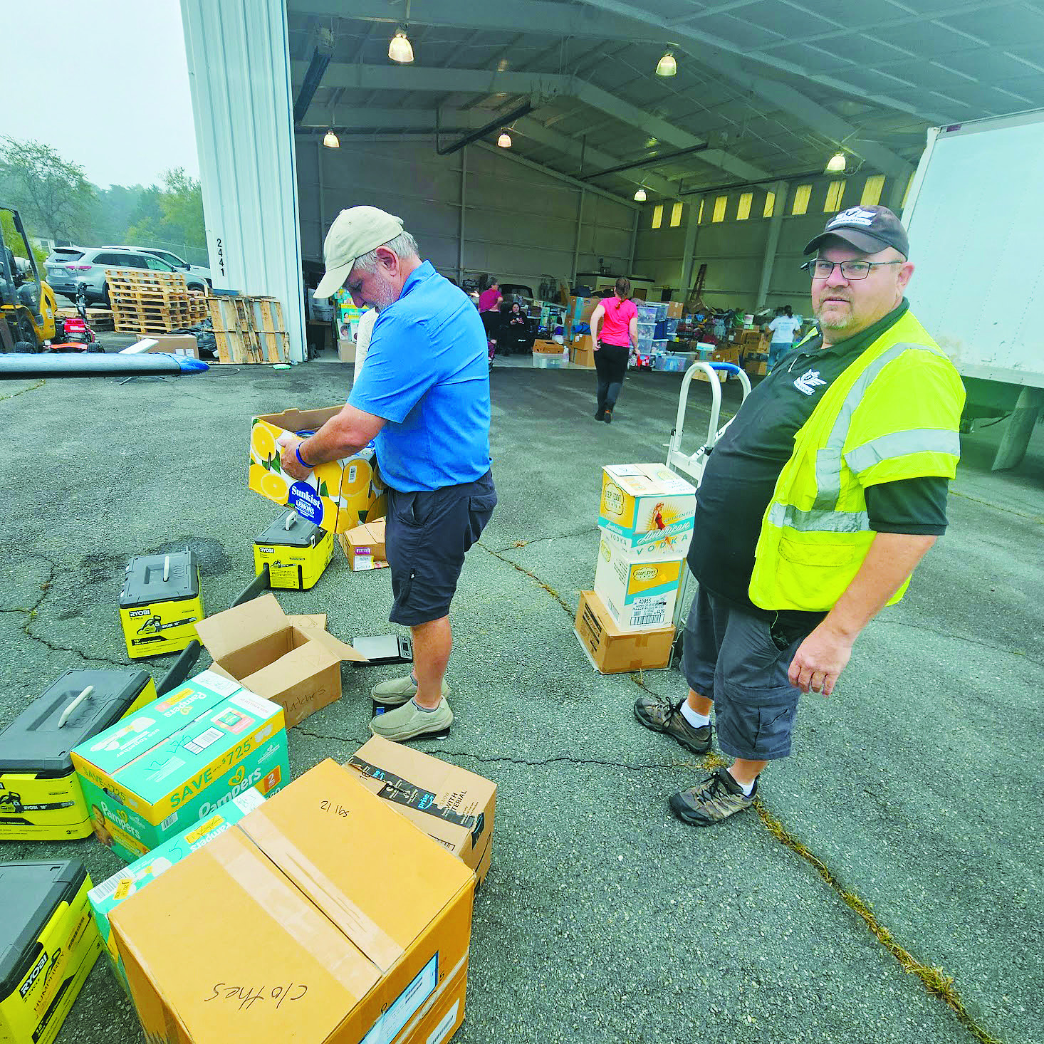 A volunteer with Brian Fredrickson (right) as they sort through supplies brought in by pilots. Fredrickson said at the height of the mission they were running around 30 supply flights per day.