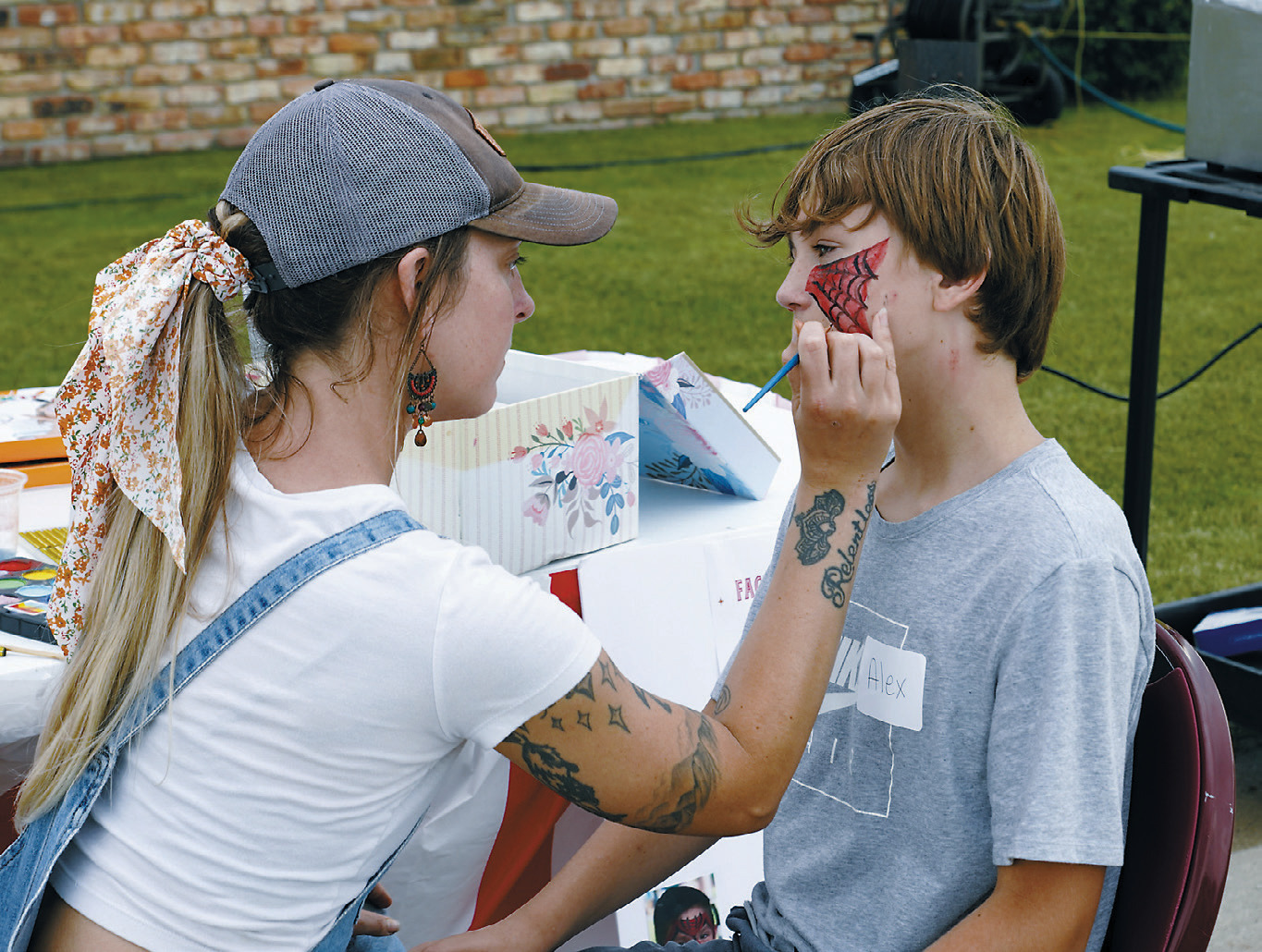 A volunteer gets his face painted SPIDERMAN-style at the Maple Manor Carnival. Photo by Larry Stokke.