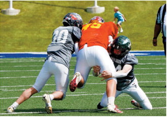 Brody Berg and a teammate bring down a West nine-man team ball carrier during the Shrine Bowl on June 20. Photo by Larry Stokke