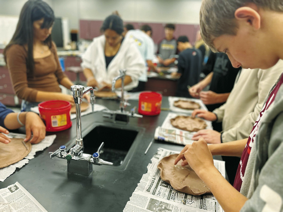 North Valley CTE students Julissa Garcia (brown shirt), Daphneiris Almonte, and Aaron Linner press prairie plants into clay plates as part of the Thinking Like a Prairie workshops. Plates will be fired and glazed and used at a potluck as part of the program next Spring. Photo Josh Anderson.