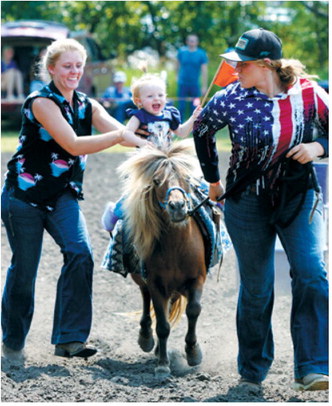 From left, Carmyn LeTexier, Sylvie LeTexier and Cheyenne participate in the pony races during Mountain’s 127th Deuce of August celebration. Photo by Larry Stokke