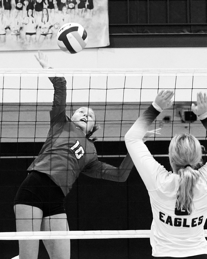 Aubrey Badding gets her hand high in the air and slams down a point for the Cards. Photo by Larry Stokke.