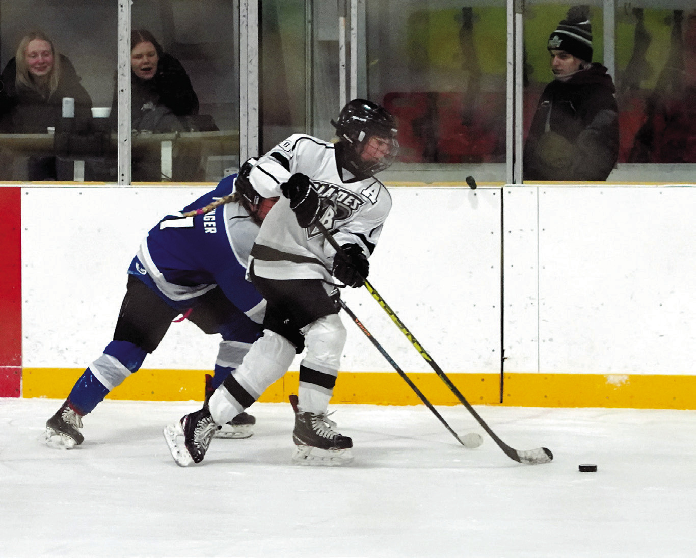 Mckenzie Regner brings the puck up the ice while under pressure from a a Bruiskie player. Photo by Larry Stokke.
