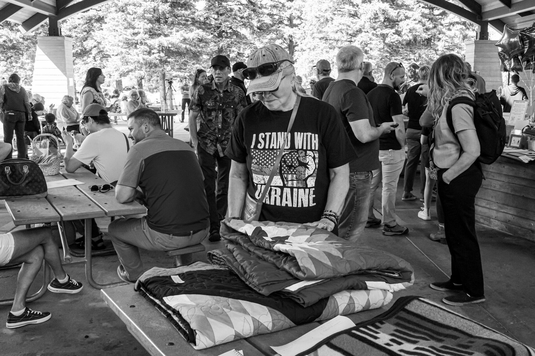 Sonja Meline from Hendrum, Minnesota, looks at a quilt included in the silent auction as part of the FM Volunteers for Ukraine International Day of Peace fundraiser at Gooseberry Park in Moorhead on Sept. 21, 2025. (Photo by W. Scott Olsen/For the North Dakota Monitor)