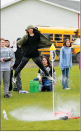 An eighth-grade student leaps into the air as a bottle rocket blasts off during the challenge. Creativity, teamwork and engineering design are all part of the project’s evaluation process. Photo by Larry Stokke