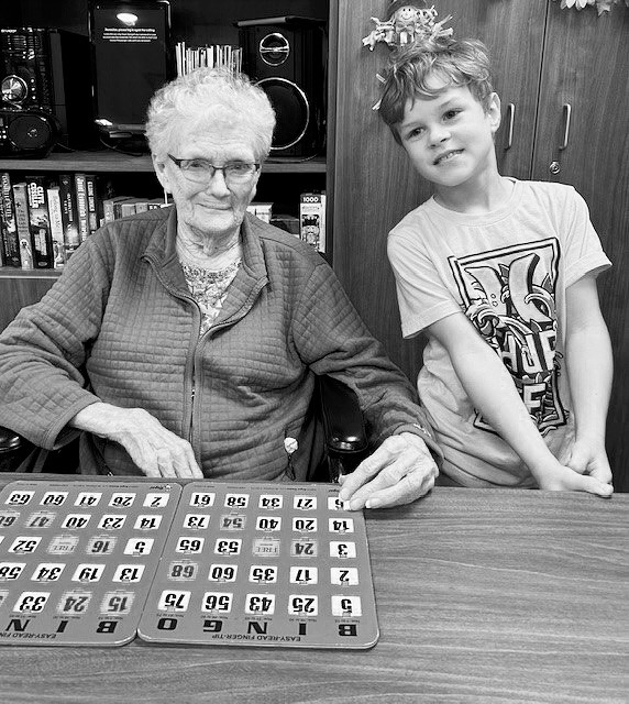 Georgie and Jett playing bingo. Darlene, Nancy, and Cade pose for a photo during the 3rd graders visit.