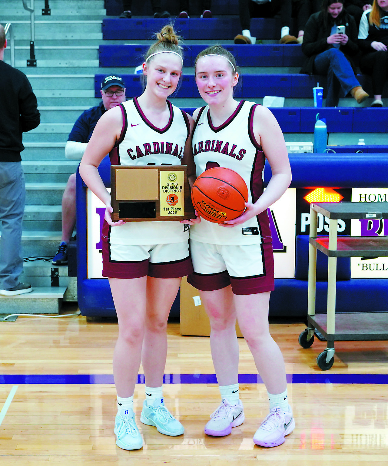 Seniors Mikaela Olson (left) and Meredith Romfo (right) with the District 3 1st place plaque and game ball. Photo by Larry Stokke.