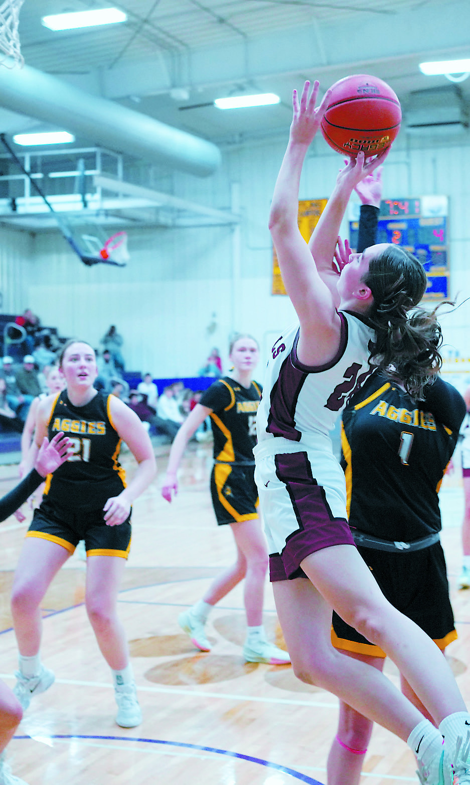 Avery Lorenz drives between two Aggie defenders and adds a bucket to her 19-point evening. Photo by Larry Stokke.