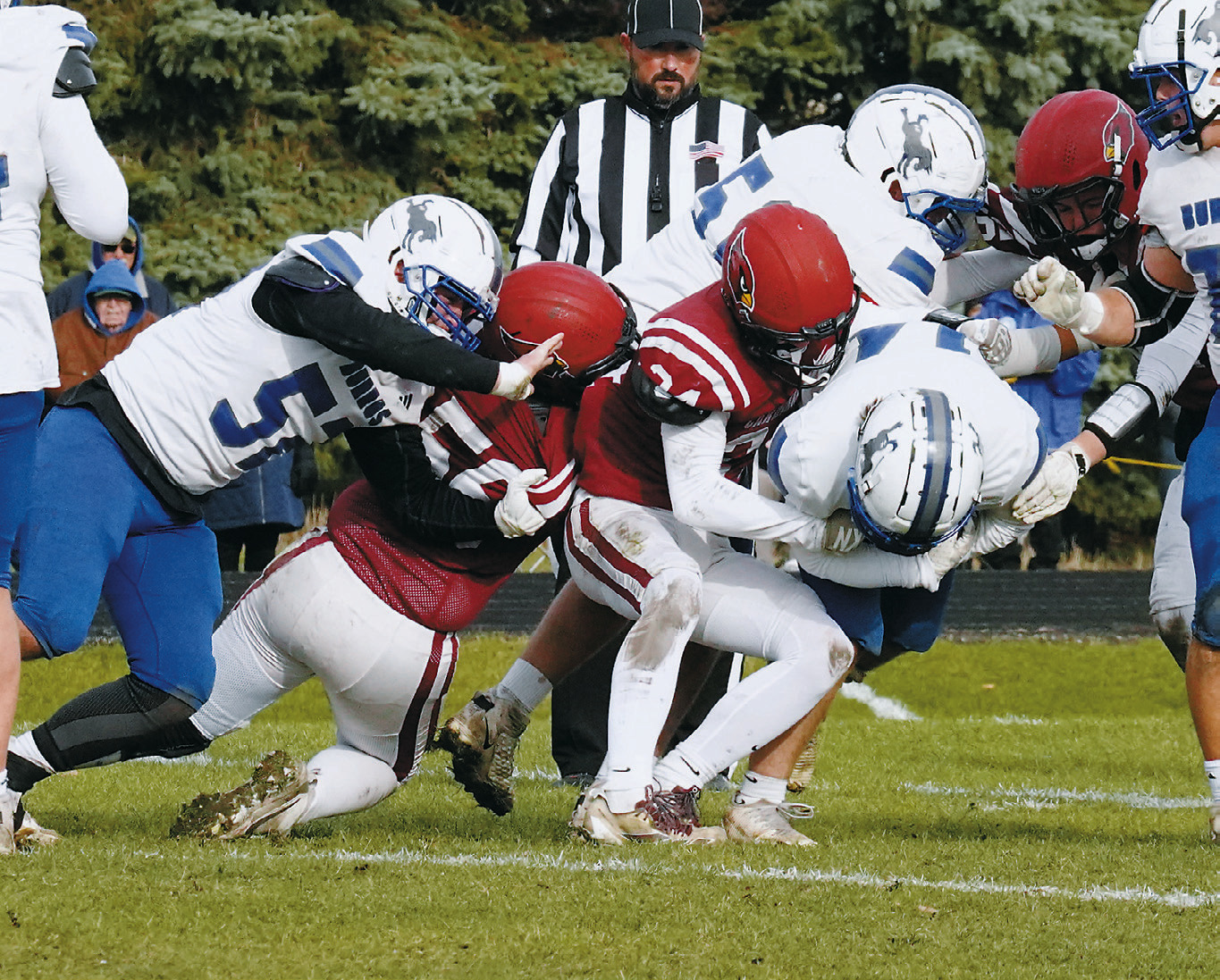 Evan Ottem, with help from teammate Landon Schneider, brings a Burros ballcarrier to the ground in the Cards’ win. Photo by Larry Stokke.