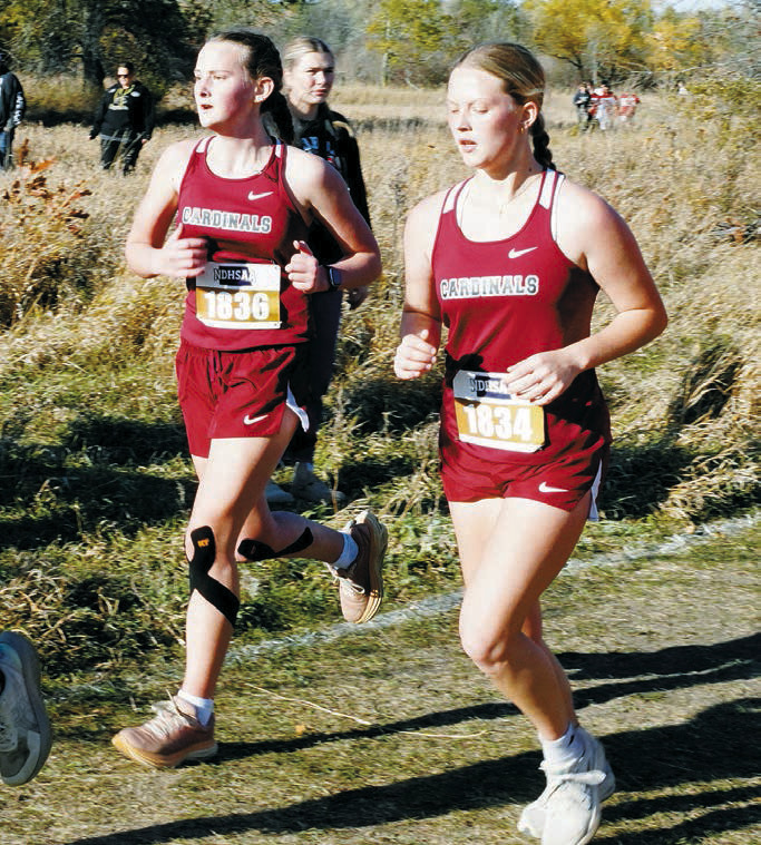 Chloe Foster and Remi Bodnar run side by side at State Cross Country Meet in Jamestown on Oct. 25. Photo by Larry Stokke.