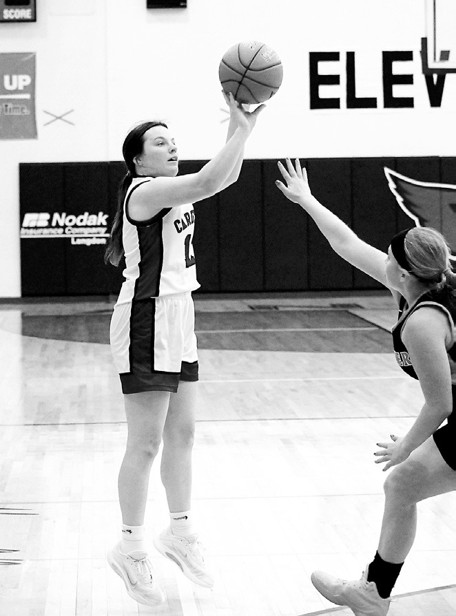 Erika Bakke adds three points to the Cardinals' score with a Tornadoes defender guarding her. Photo by Larry Stokke.