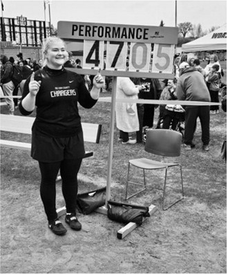 Dagan Slade of Nelson County poses with the scoreboard after winning her second consecutive North Dakota state shot put championship with a throw of 47 feet, 5 inches. Slade is the granddaughter of Ron and Lenna Schill of Langdon and the daughter of Rebecca (Schill) Slade, a member of the Langdon High School Class of 1995. Submitted photo.