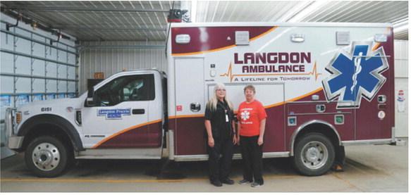 Lorraine Gage, left, and Sheila Beauchamp stand beside a Langdon Ambulance Service unit after being recognized by the National Registry of Emergency Medical Technicians for achieving 40 consecutive years of National EMS Certification. Photo by Larry Stokke