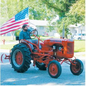 A vintage Allis-Chalmers tractor carrying an American flag makes its way through the Pre-Blast Bash parade. Photo by Larry Stokke