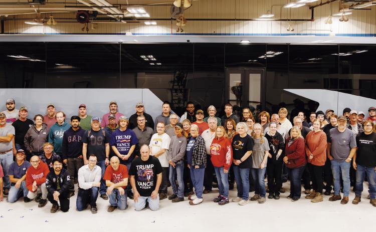 The MCI Pembina team pose in front of their first electric coach assembled at the plant.