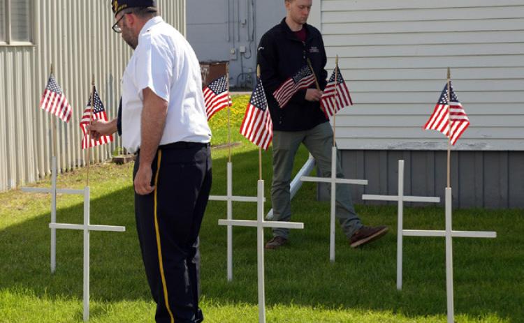 Commander Scott Anderson (left) places flags atop crosses along with Alan Hiltner (right). Alan, Adjunct Leon Hiltner’s son, is a member of the Sons of the American Legion. Photo by Larry Stokke.