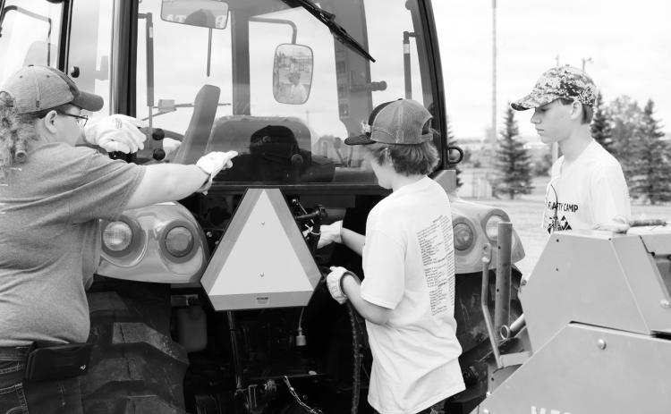 Teen farm safety camp participants demonstrate how to properly connect hydraulic hoses and power take-off shafts of farm equipment to a tractor. (NDSU photo)