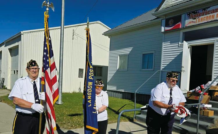 After a brief ceremony, Langdon American Legion Post 98 members honorably disposed of worn, tattered, and faded American flags last week. Daryl Kempel (left) and Anna Spivey (middle) stood as Honor Guards while Dennis Hansel (right) prepared a U.S. flag for burning.
