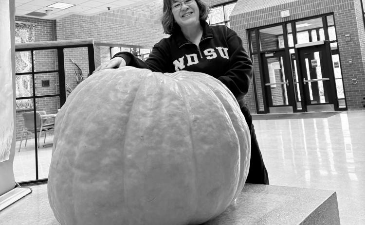 Esther McGinnis, NDSU Extension horticulturist, stands next to a giant pumpkin on the NDSU campus, and shares some little-known facts about pumpkin in this week's Dakota Gardener. (NDSU photo)