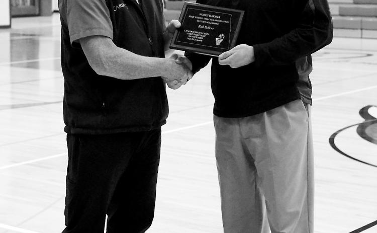 Coach Scherr (right) receives a plaque from Daren Christianson (left) after Scherr reached a milestone with his 500th win during the 2024-2025 Girls Basketball Season. Photo by Larry Stokke.