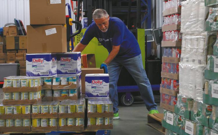 John Hoffman, a volunteer at the Dream Center in Bismarck, moves boxes of food from a pallet to a shelf in the facility storage area on Aug. 5, 2026. (Photo by Michael Achterling/North Dakota Monitor)
