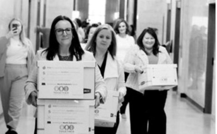 Michelle Wagner, left, carries boxes of signed petitions for a proposed ballot measure to make public school breakfasts and lunches free in North Dakota on April 9, 2026, at the Capitol. To her right is Amy Jacobson and Ashley Gaschk. All three are members of the sponsoring committee for the measure. (Photo by Mary Steurer/North Dakota Monitor)