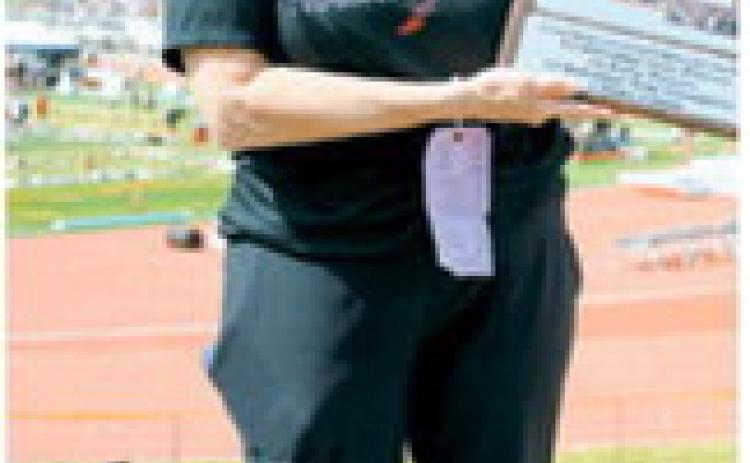 Jane Hart poses with a plaque recognizing her 42 years of dedication to Langdon Area track and field, honoring a coaching career that spanned from 1984 to 2026 and the accomplishments of countless athletes she mentored along the way. Photo by Larry Stokke