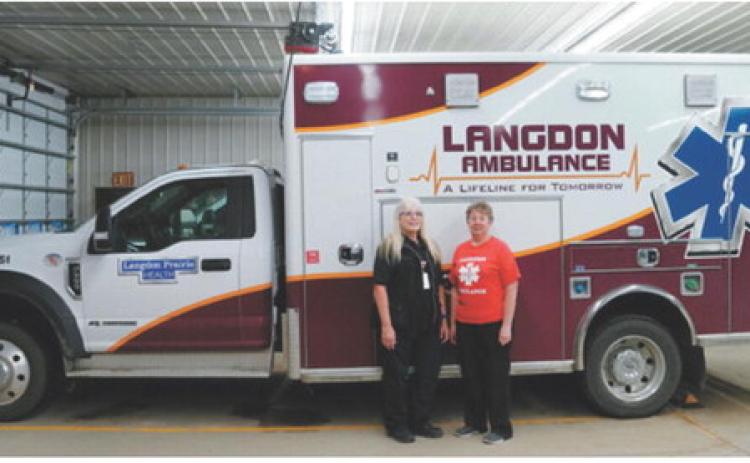 Lorraine Gage, left, and Sheila Beauchamp stand beside a Langdon Ambulance Service unit after being recognized by the National Registry of Emergency Medical Technicians for achieving 40 consecutive years of National EMS Certification. Photo by Larry Stokke
