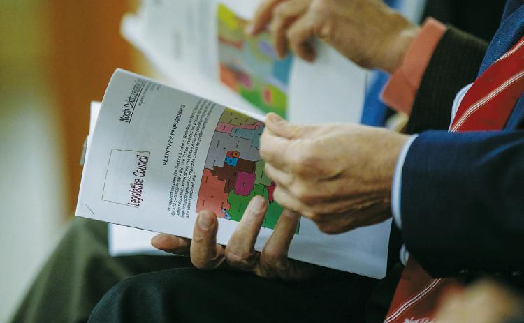 Legislators attending a Redistricting Committee meeting Dec. 13, 2023, look at maps of different proposals. (Photo by Kyle Martin/For the North Dakota Monitor)