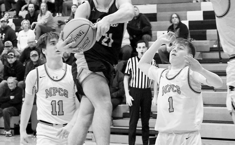 Player of the Game Brody Berg leaps high and drops one in a basket to finish the game with 17 points versus MPCG. Photo by Larry Stokke.