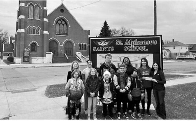Students are pictured with Janelle Bata, Pembina Gorge Dirt Riders and Alyssa Plummer, president of the St. Alphonsus School Committee. The dirt riders made a $1,000 donation to the school committee in November. Submitted photo