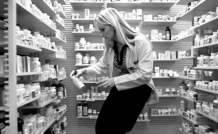 A pharmacy manager retrieves a bottle of antibiotics. (Photo by Joe Raedle/Getty Images)